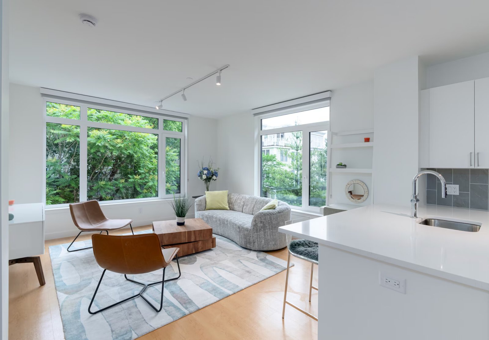 Furnished living room with open kitchen and large windows, no people